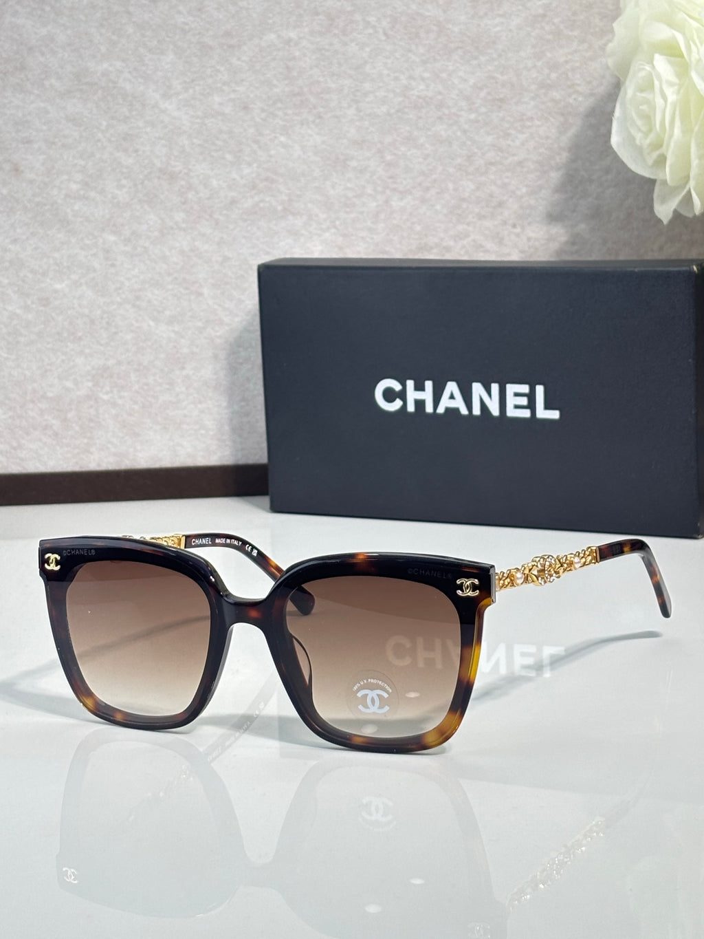 Chanel sunglasses with tortoiseshell frames and brown-tinted lenses, gold chain temples