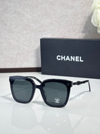 Chanel sunglasses with dark frames, dark lenses, and gold chain details on arms
