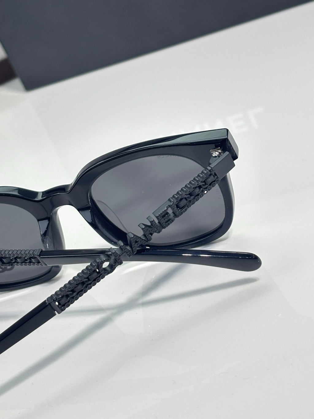Chanel sunglasses side view with black lens and textured black temple strap detail