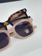 Chanel sunglasses close-up with dark lens and mixed tortoiseshell and pale pink frame