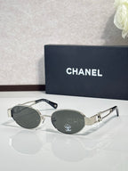 Round sunglasses with dark frame and dark lenses, gold metal logo on temple