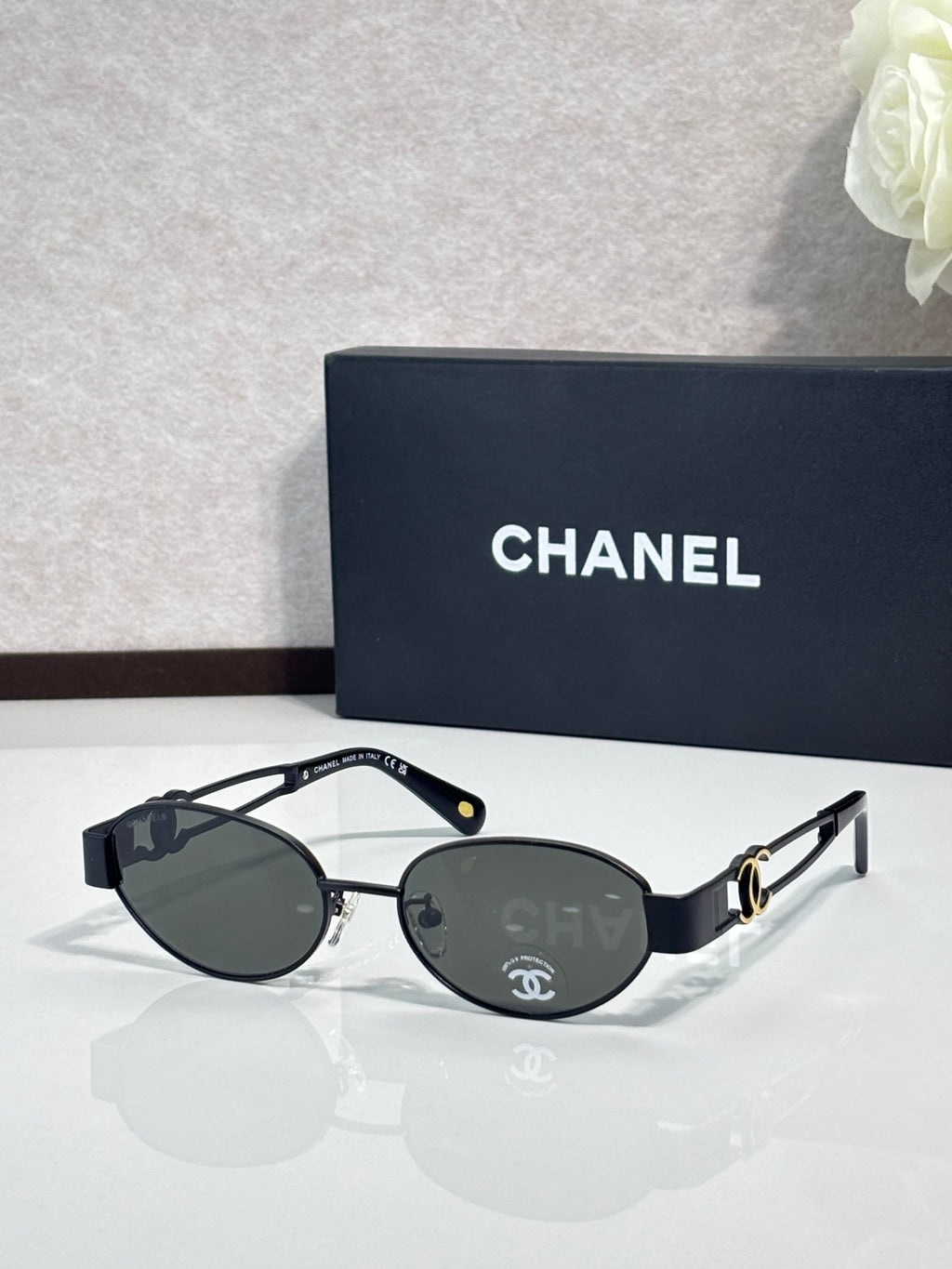 Round sunglasses with black frame and dark lenses, gold logo detail on temple