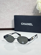 Round sunglasses with black frame and dark lenses, gold logo detail on temple