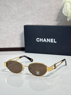 Round sunglasses with gold frame and brown-tinted lenses, logo detail on temple