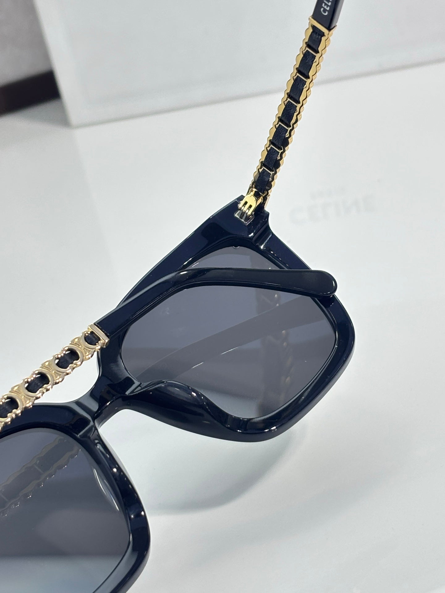 Celine sunglasses close-up of dark lenses and gold chain temple detail