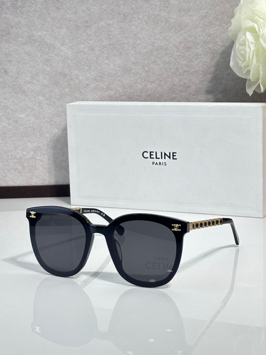 Sunglasses with dark blue frames and dark lenses, gold-tone logo studs on temples