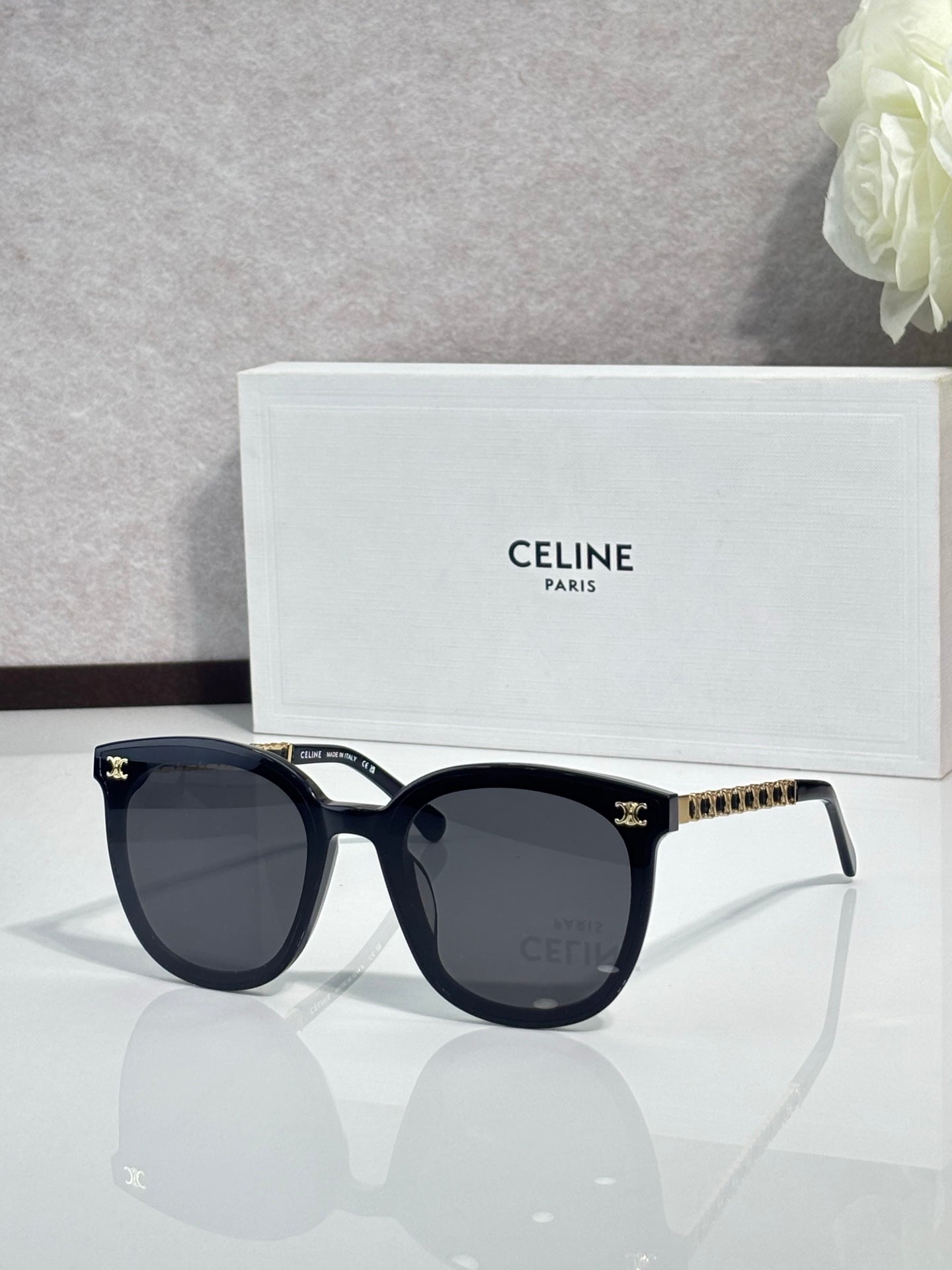 Sunglasses with dark blue frames and dark lenses, gold-tone logo studs on temples