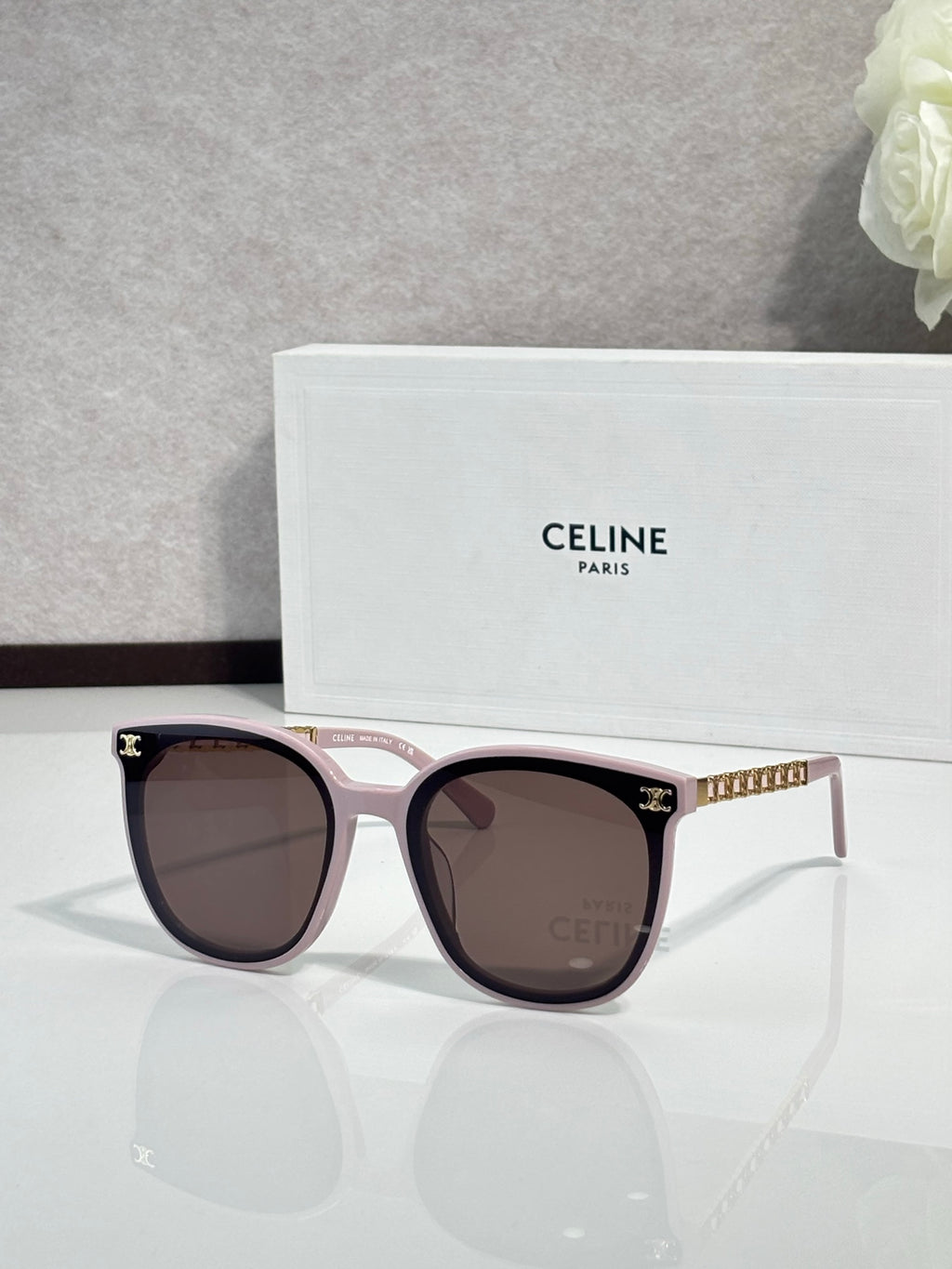 Sunglasses with light pink frames and brown lenses, gold-tone logo detail temples