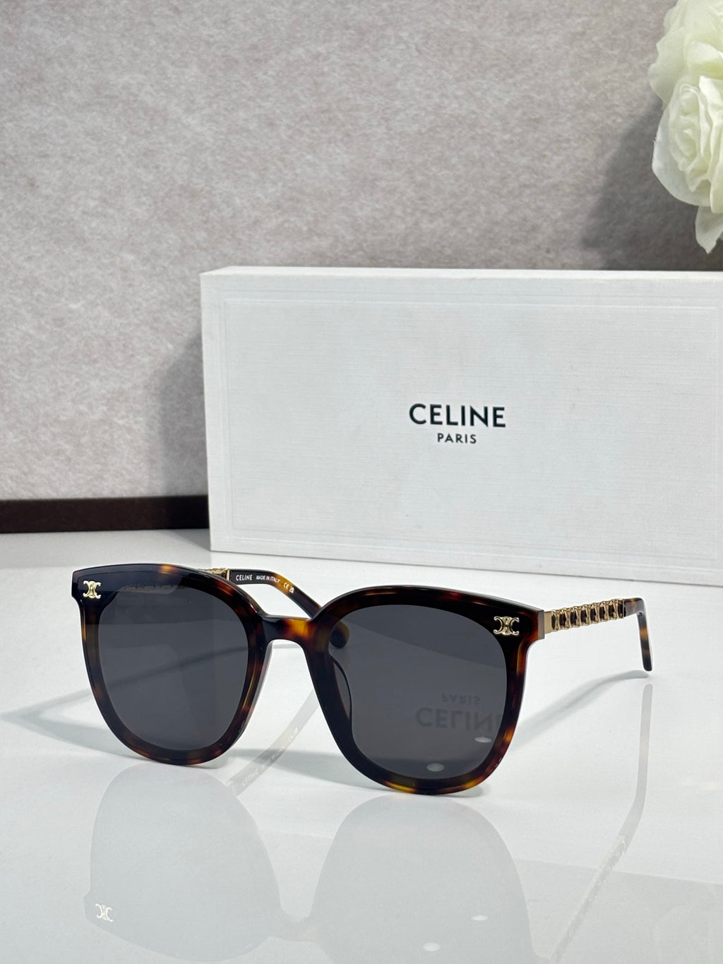 Tortoiseshell sunglasses with dark lenses, gold-tone logo details on the temples