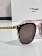 Pink sunglasses with dark lenses, gold chain-like trim along the upper edge