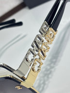 Chanel gold-tone temple arm with patterned letters and rhinestone-like studs