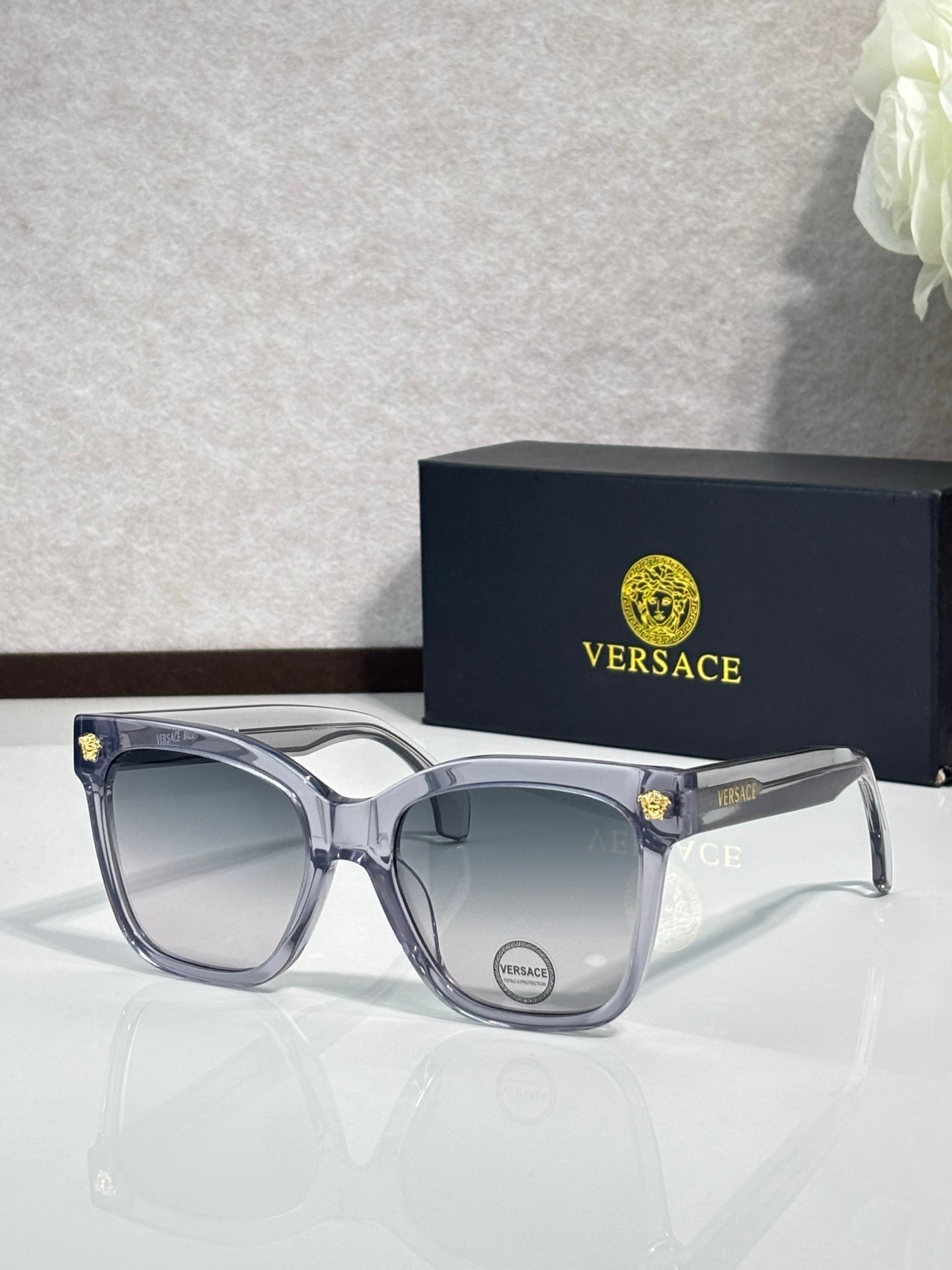 Versace sunglasses with translucent gray frames and gray lenses, gold emblem at temple