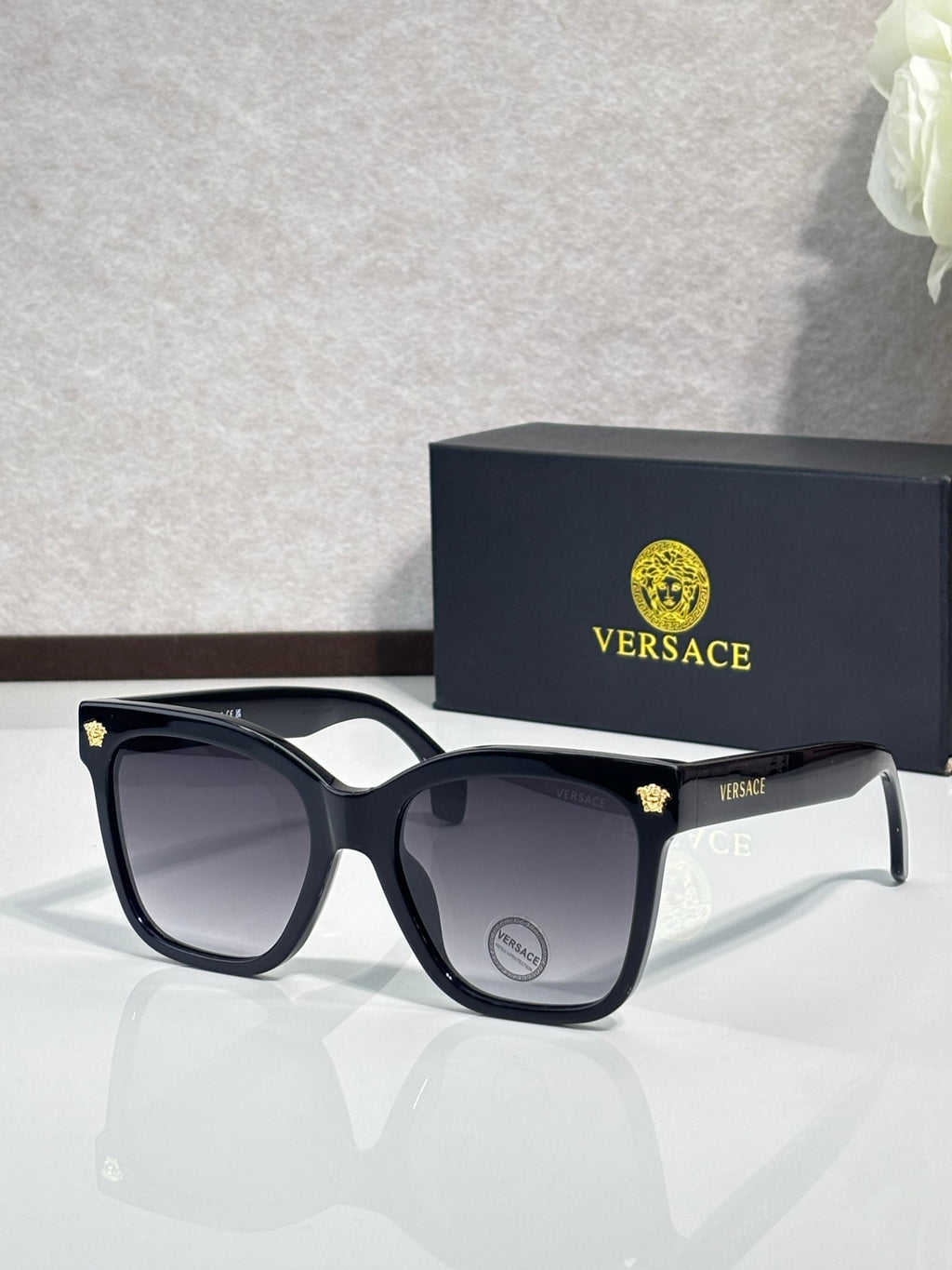 Versace sunglasses with black square frames and dark lenses, silver arms with VERSACE logo