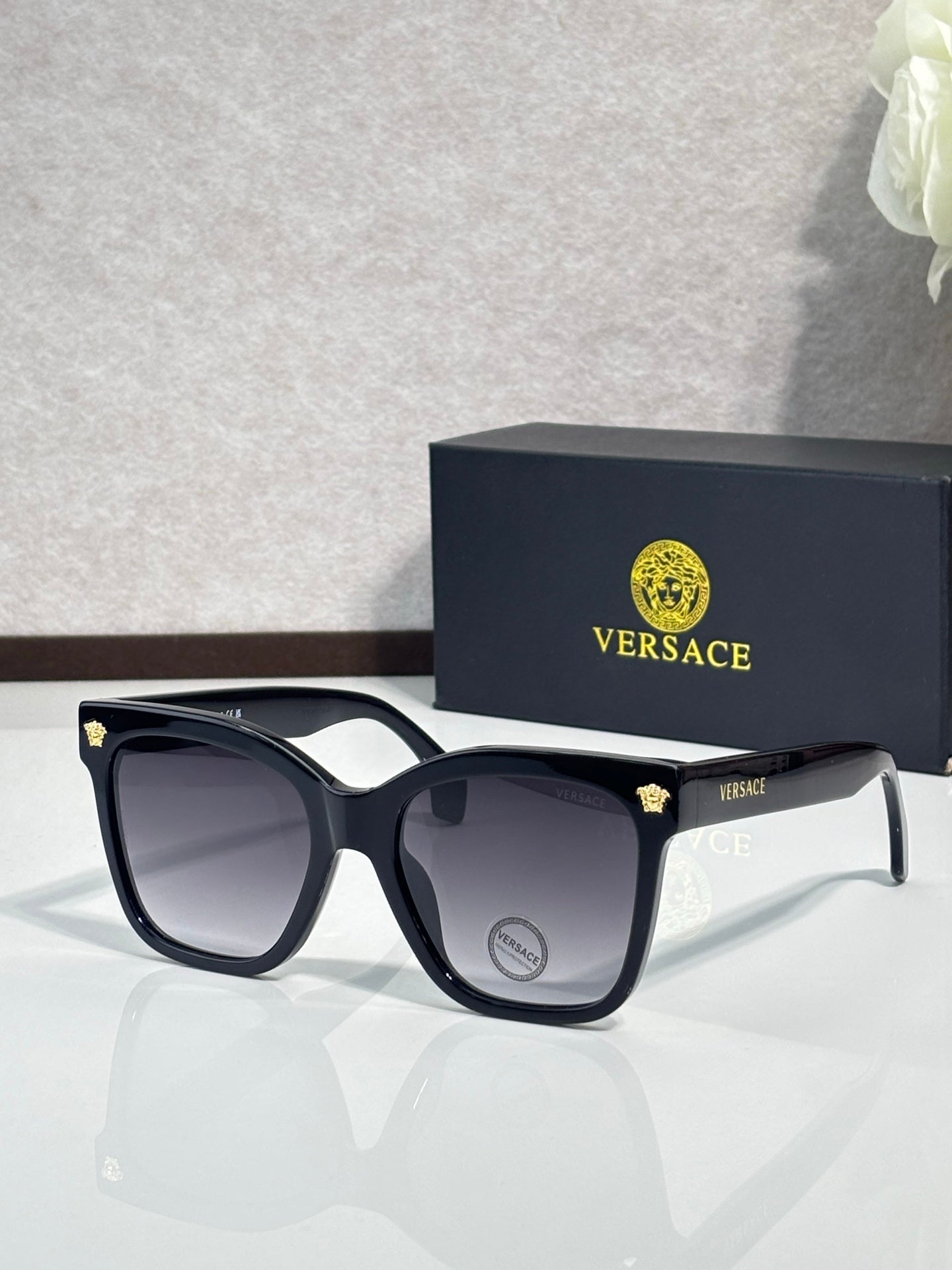 Versace sunglasses with black square frames and dark lenses, silver arms with VERSACE logo