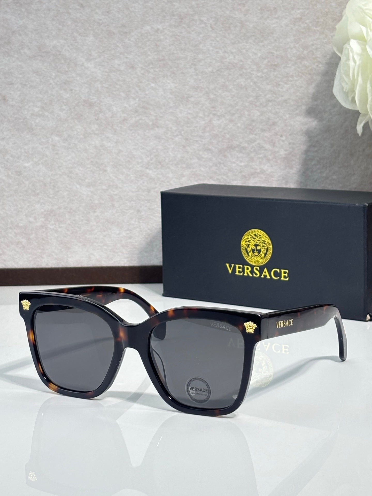 Versace sunglasses with tortoiseshell frames and dark lenses, gold emblem detail on corner