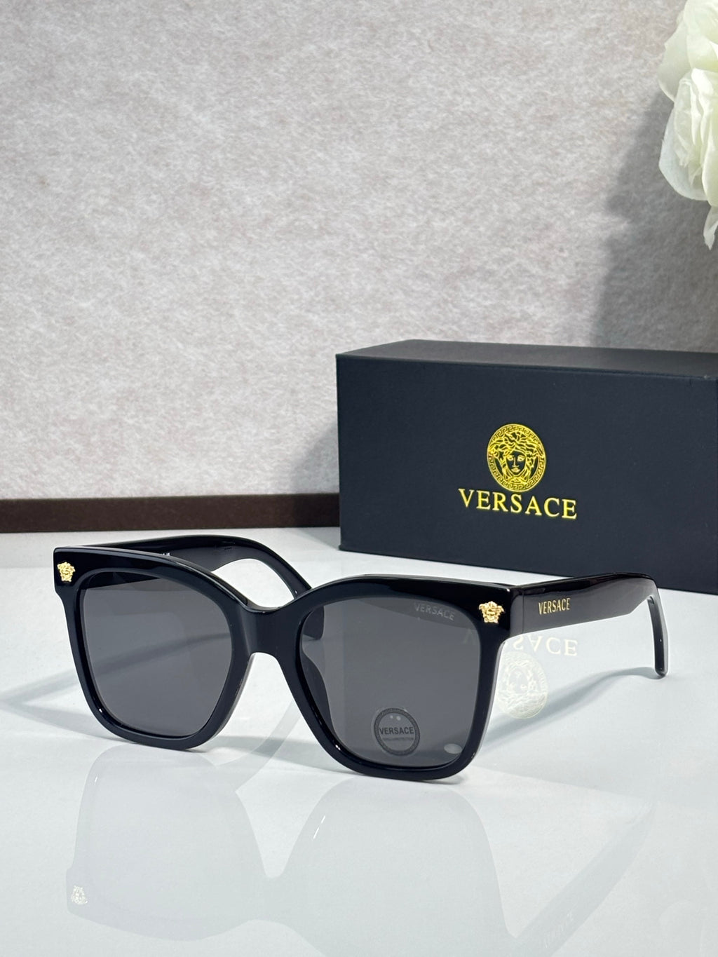 Versace sunglasses with black square frames and dark lenses, gold emblem on temple