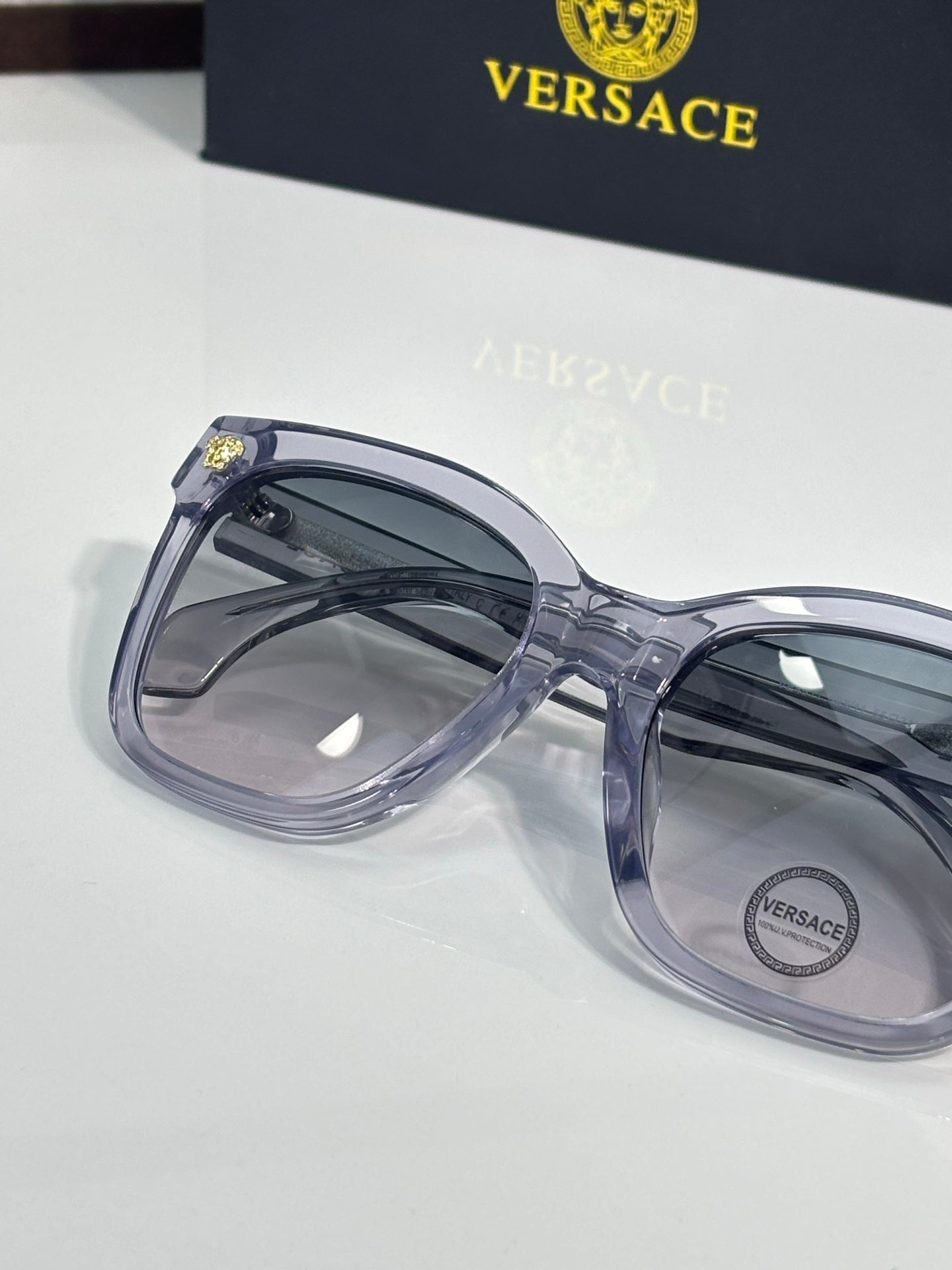 Versace eyeglass frames with translucent blue temples and dark lenses, gold emblem hinge