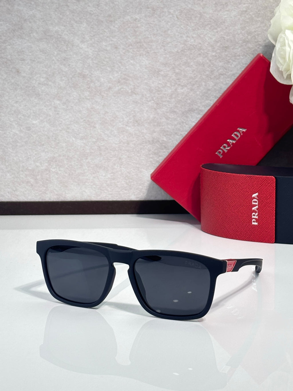 Prada square sunglasses with dark lenses and navy-blue frame, light gray temples