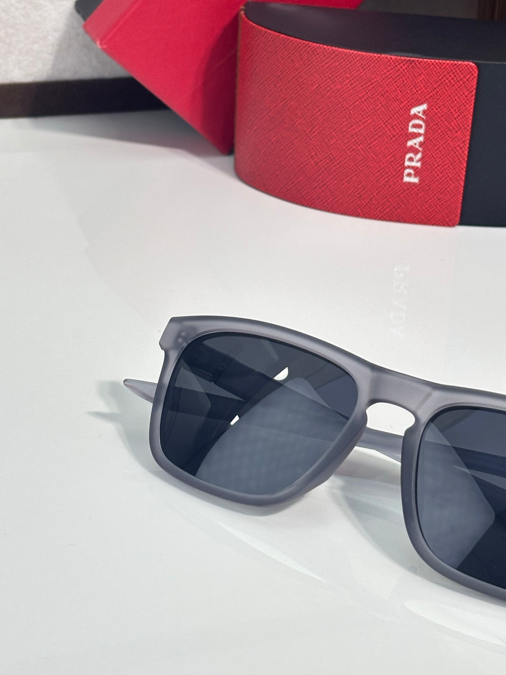 Prada square sunglasses with dark lenses and gray frame, angled close-up