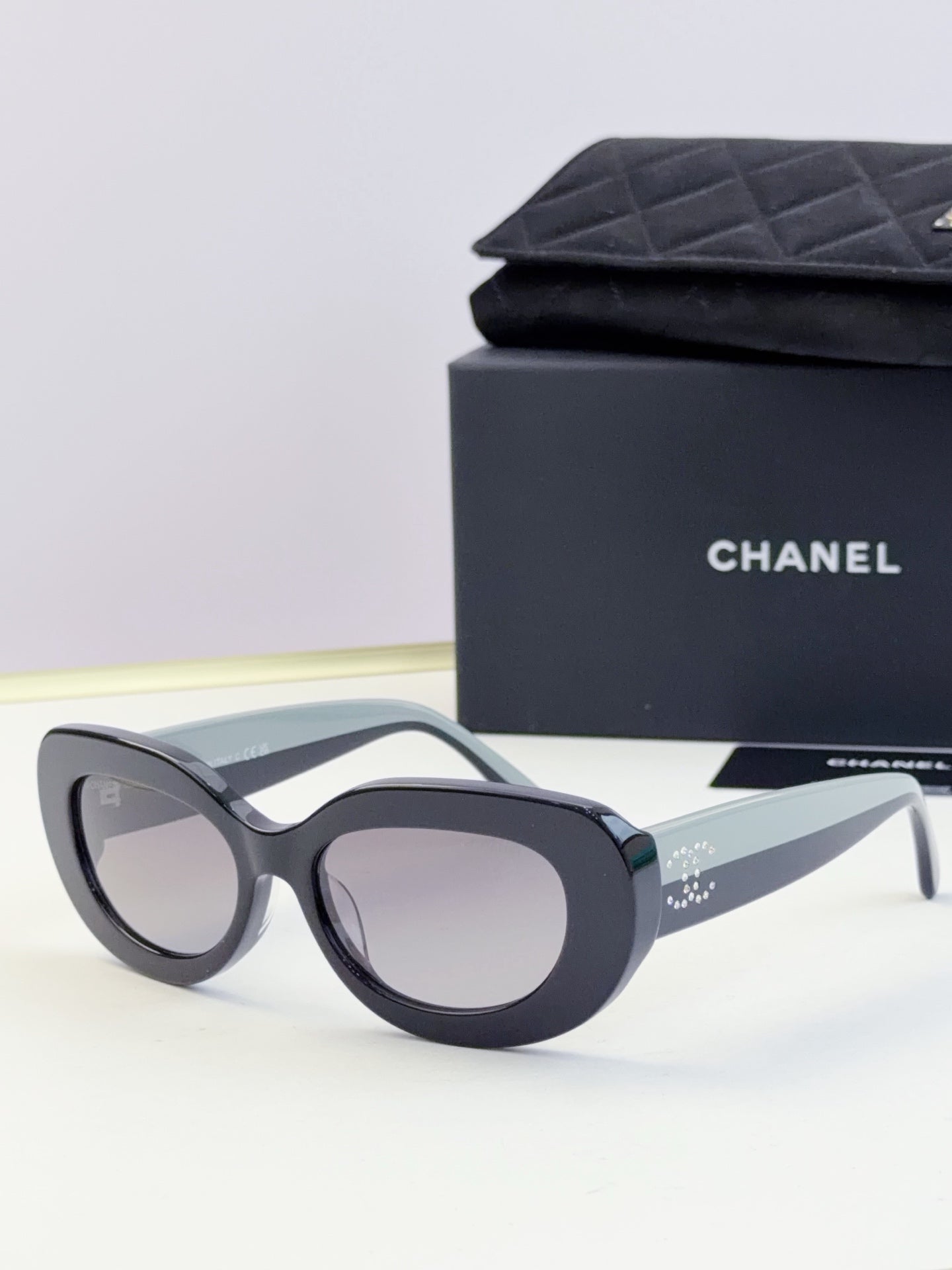 CHANEL sunglasses with dark lenses and black cat-eye frame, side angle