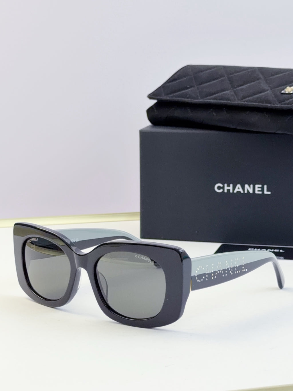 Chanel sunglasses with dark blue frames and light gray lenses, side arm with sparkle strip