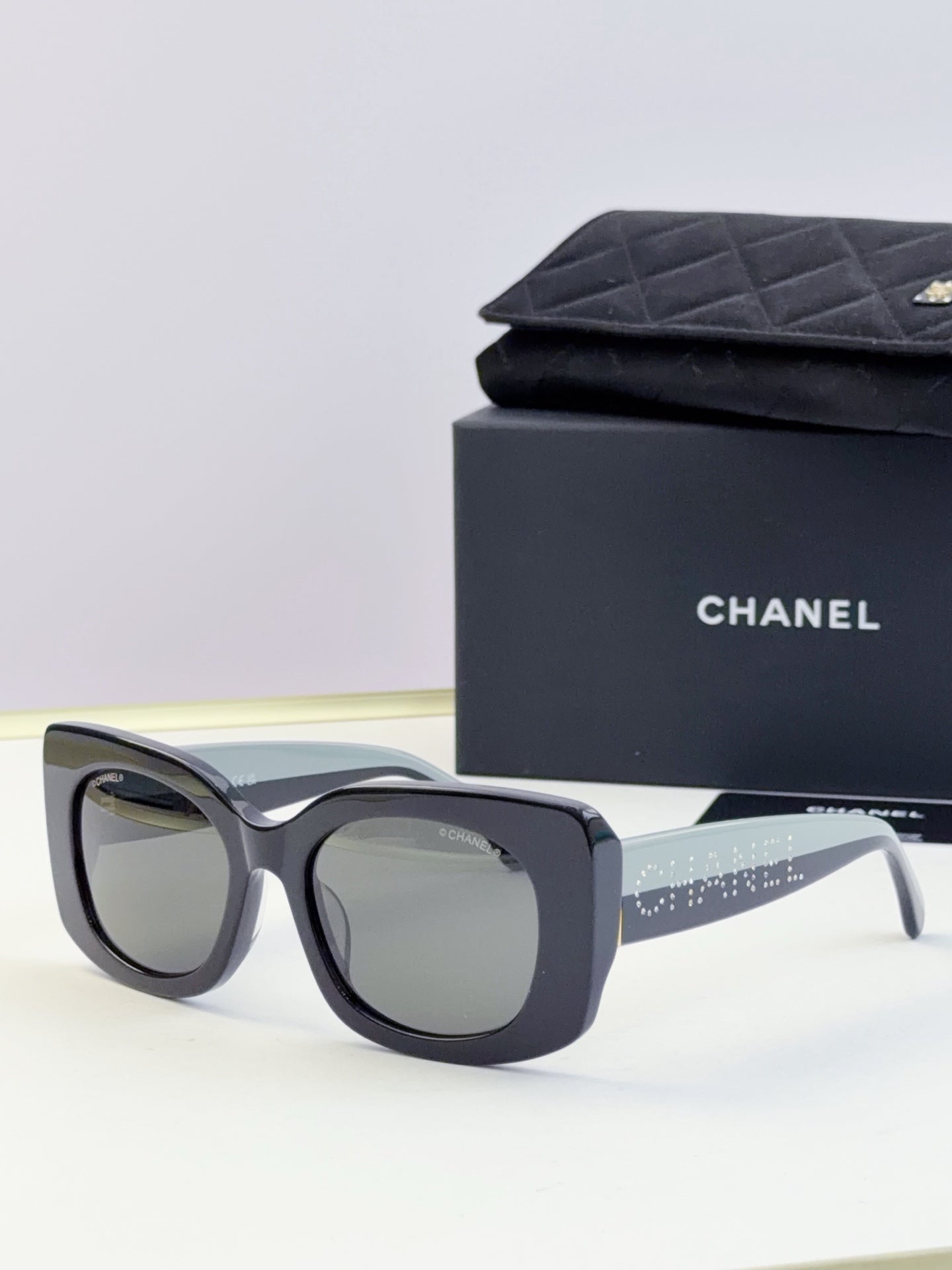 Chanel sunglasses with dark blue frames and light gray lenses, side arm with sparkle strip