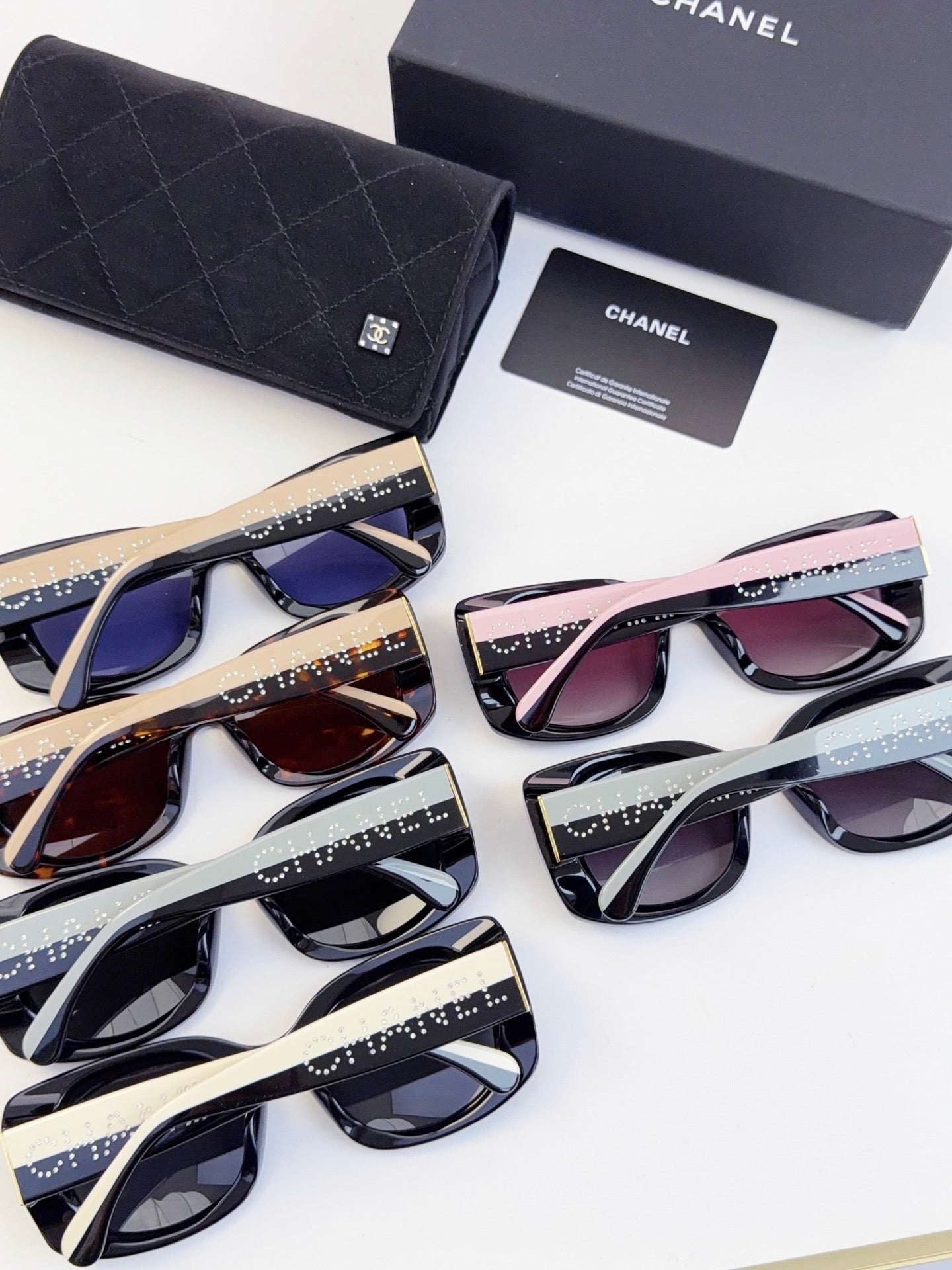 Assorted Chanel sunglasses with mixed frames and tinted lenses, displayed with a dark case