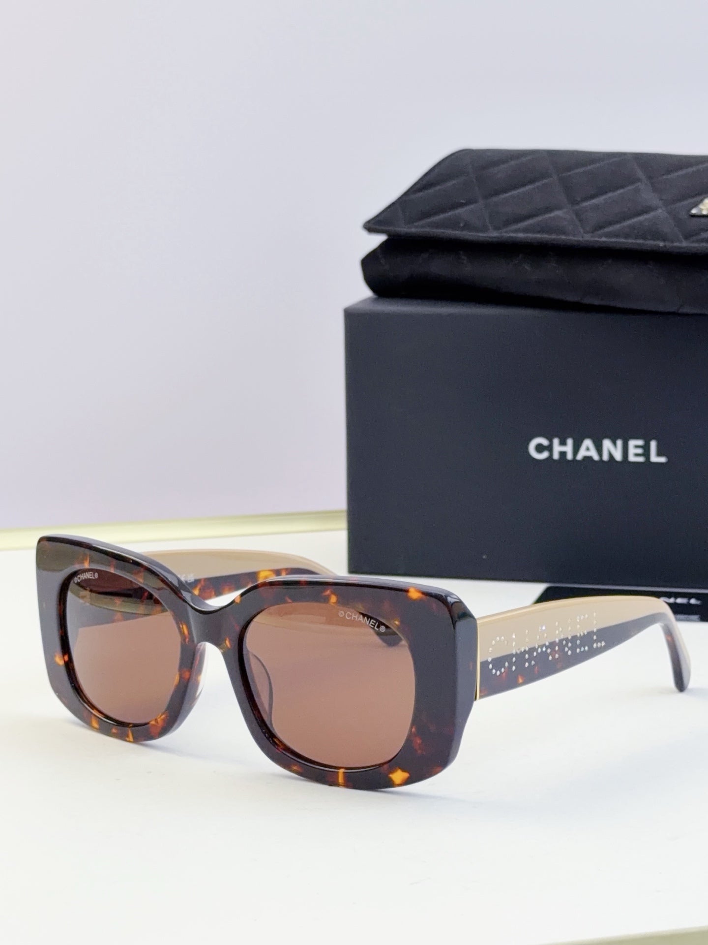 Chanel sunglasses with dark blue tortoise-style frames and warm brown lenses