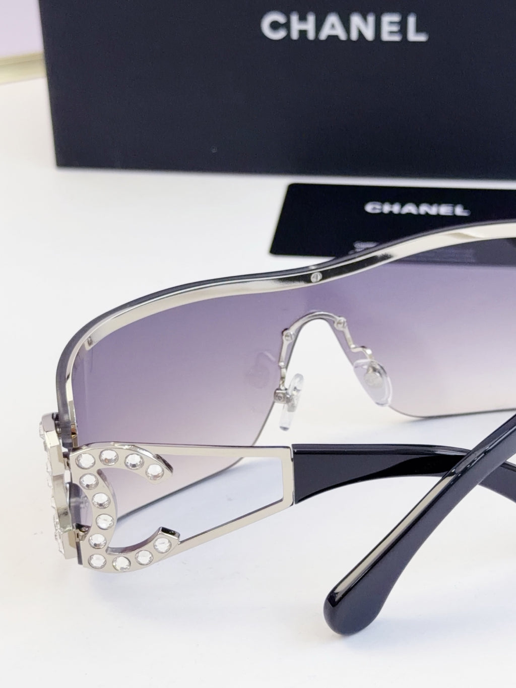 Sunglasses side view with smoky gradient lenses and gold-tone metal frame, CHANEL logo