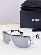 Sunglasses with blue gradient lenses and gold-tone frame, rhinestone CC-style emblem