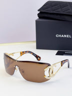 Sunglasses with brown gradient lenses and gold-tone frame, rhinestone CC-style emblem