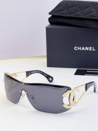 Sunglasses with pale blue lenses and gold-tone frame, rhinestone CC-style emblem