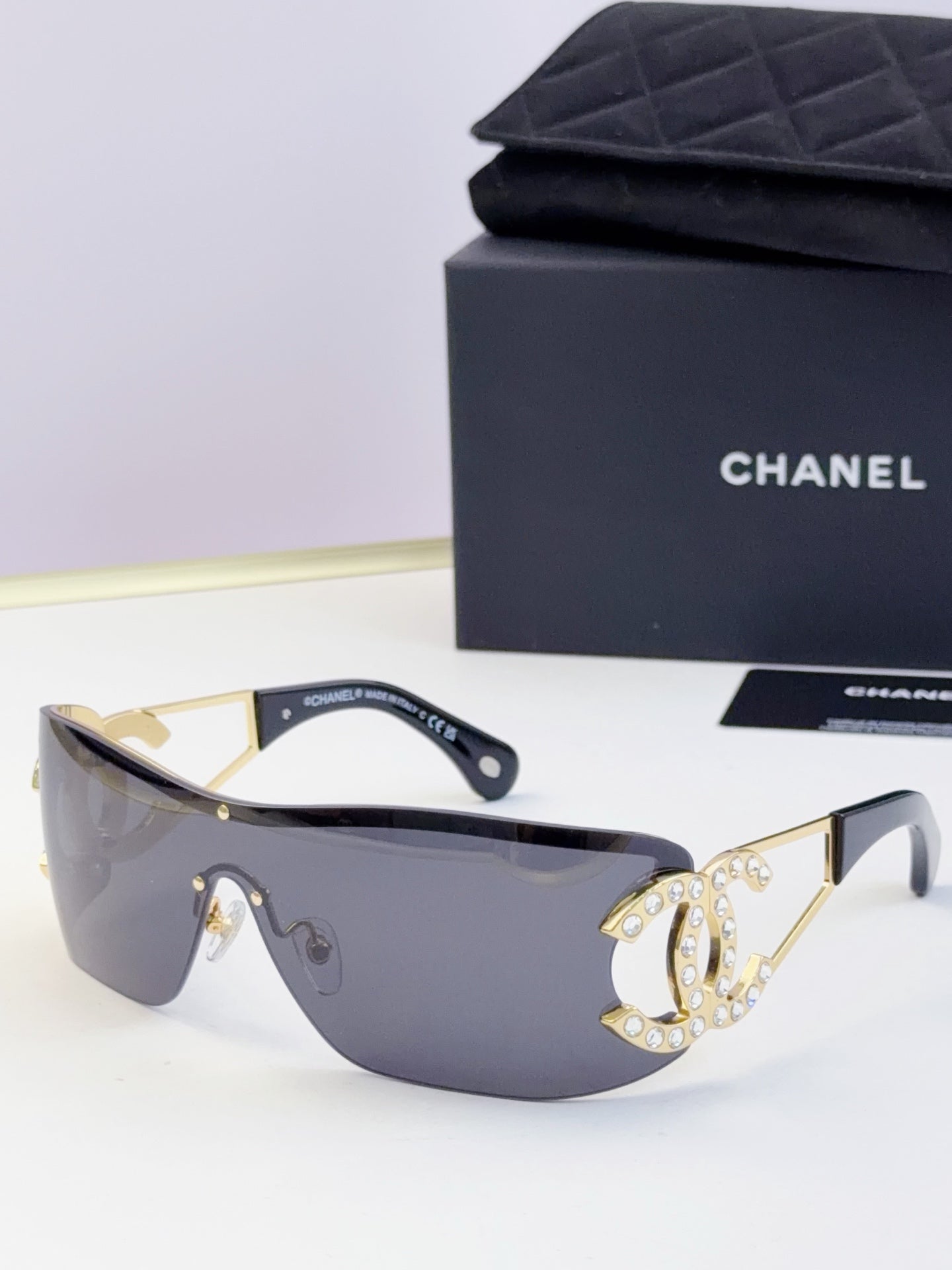 Sunglasses with pale blue lenses and gold-tone frame, rhinestone CC-style emblem