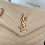 Beige YSL flap bag close-up of gold YSL logo on quilted front