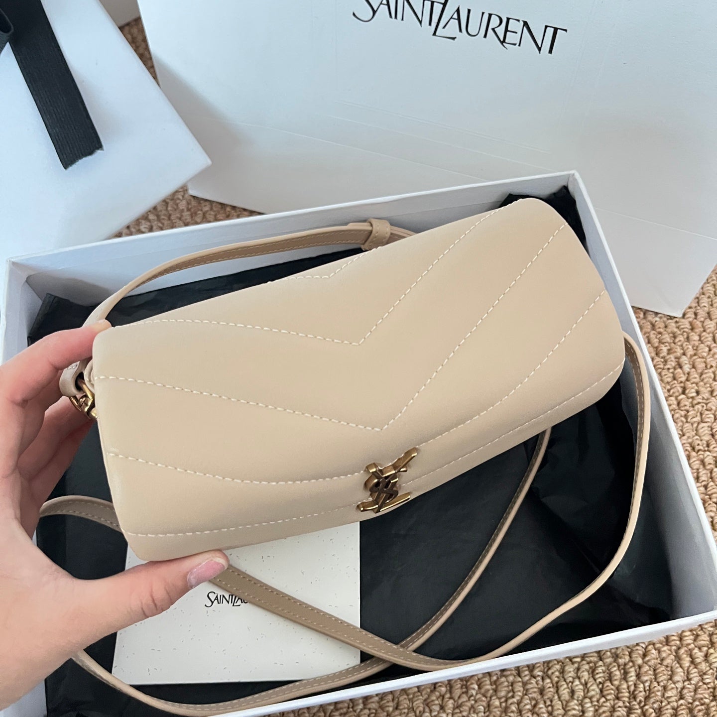 Beige YSL shoulder bag with flap and crossbody strap held in hand