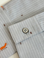 Close-up of light blue striped collar and button with orange dog embroidery