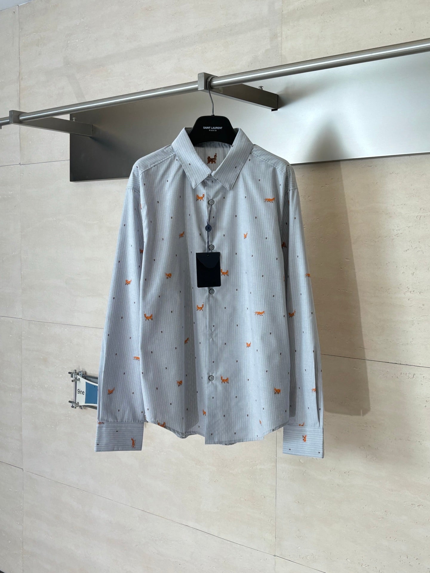 Light blue long-sleeve button-up shirt with orange dog embroidery, on a hanger