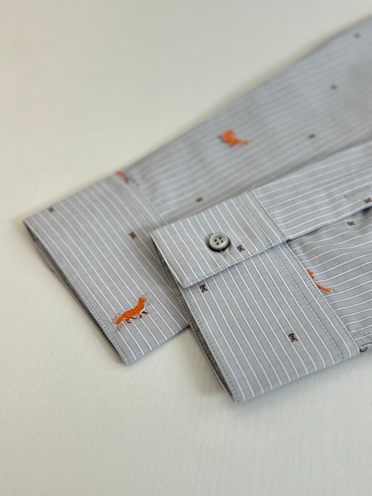 Light blue striped shirt cuffs with orange dog embroidery and two-button detail