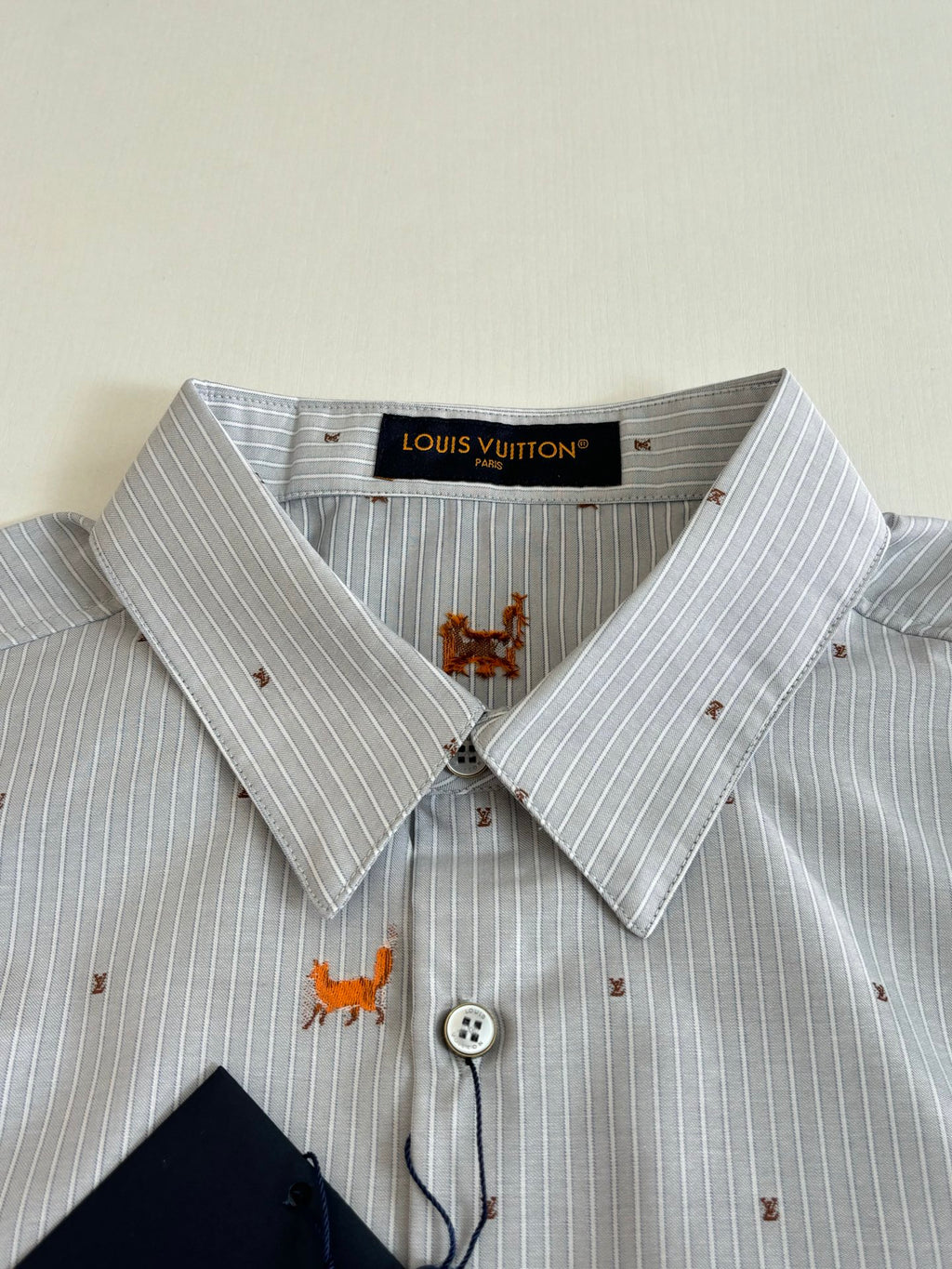 Light blue striped dress shirt collar with orange dog embroidery and button placket