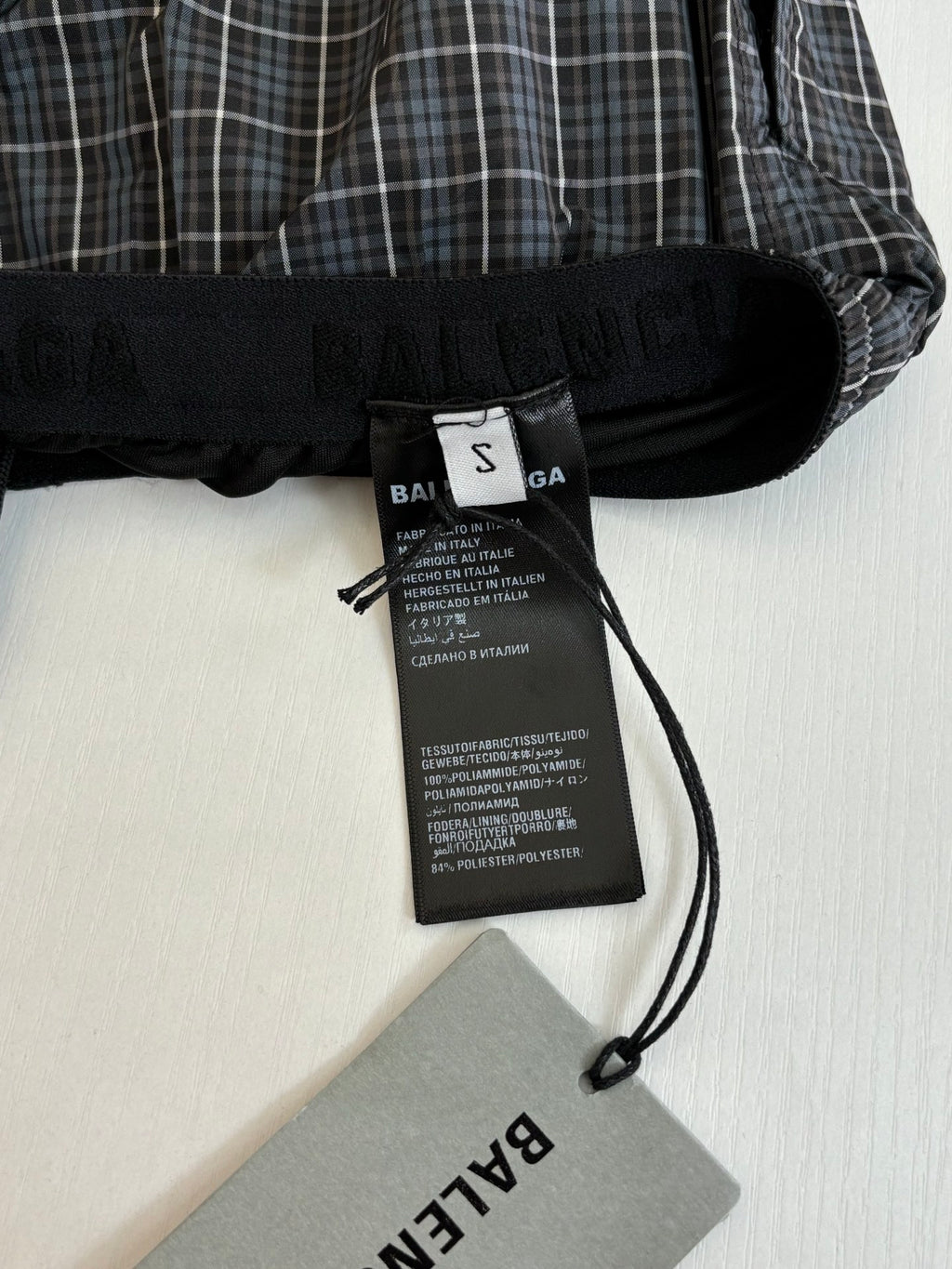 Balenciaga care label tag on black waistband of plaid shorts