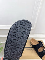 Sandal outsole with dark textured tread, monogram strap visible behind