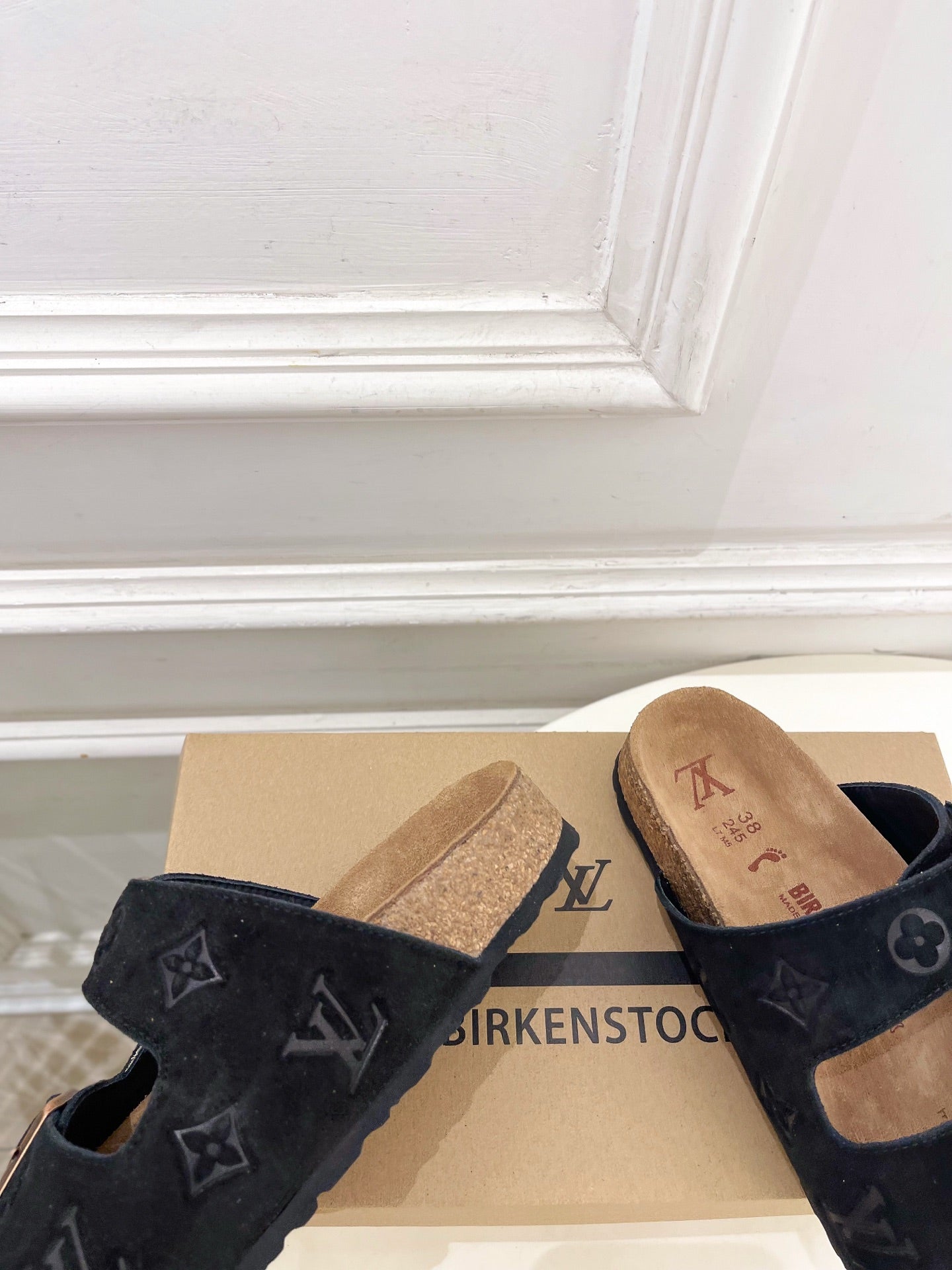 Monogram sandals with black straps and silver buckles, tan cork footbeds close-up