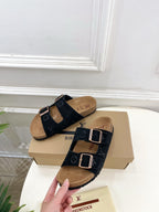 Monogram sandals with black double straps and silver buckles over tan footbeds
