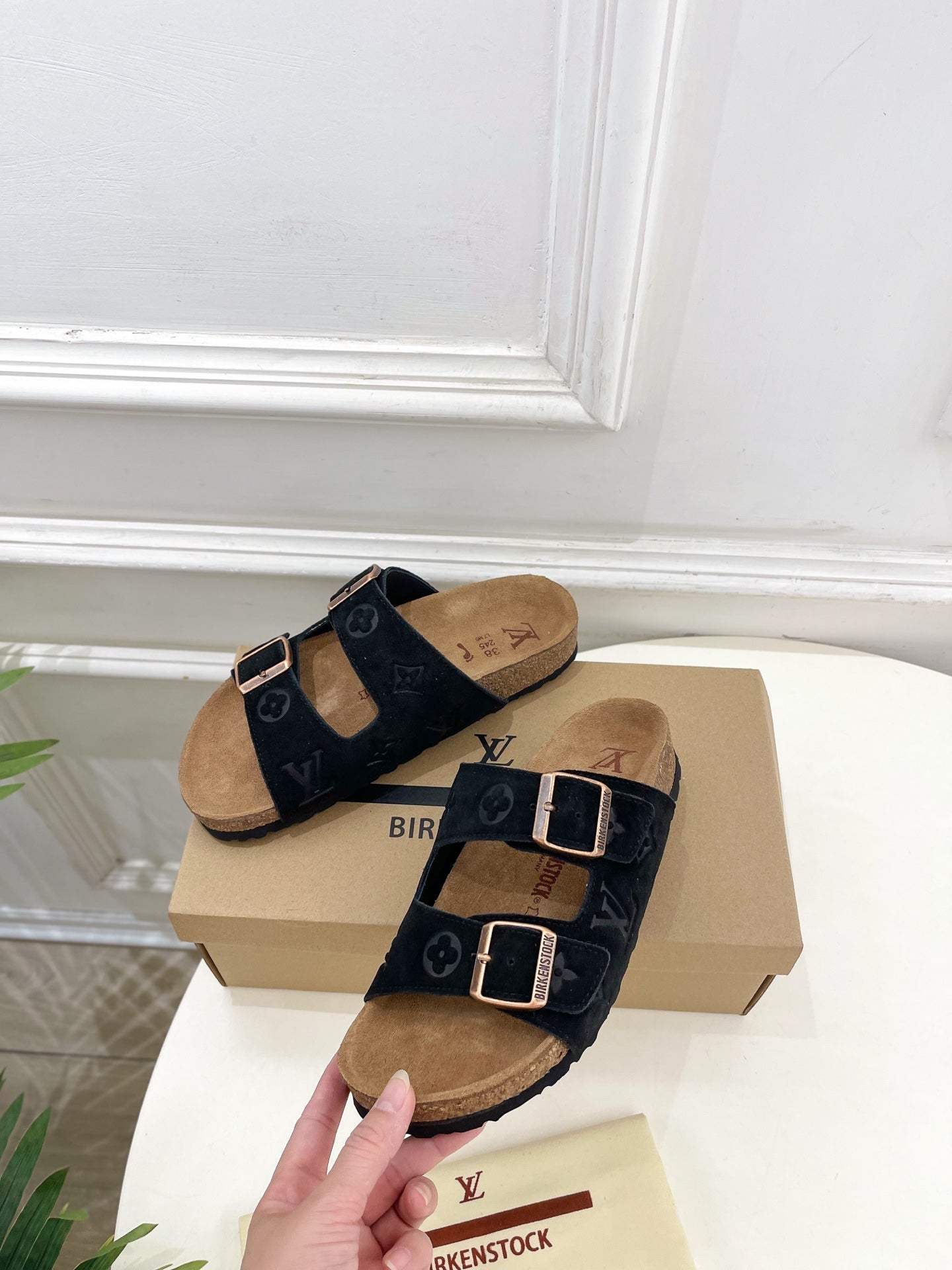 Monogram sandals with black double straps and silver buckles over tan footbeds