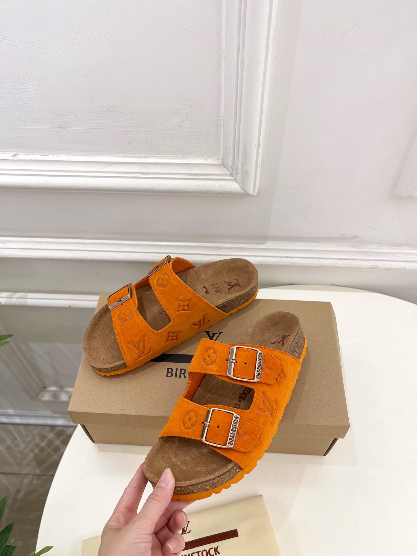 Orange Louis Vuitton sandals with two buckled straps over brown footbed, top view.