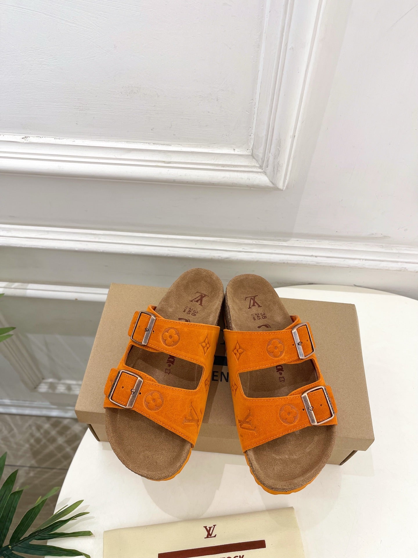 Orange Louis Vuitton sandals with two buckled straps and brown footbed.