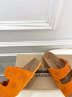 Orange Louis Vuitton sandals with buckled straps, brown footbed and textured sole edge.