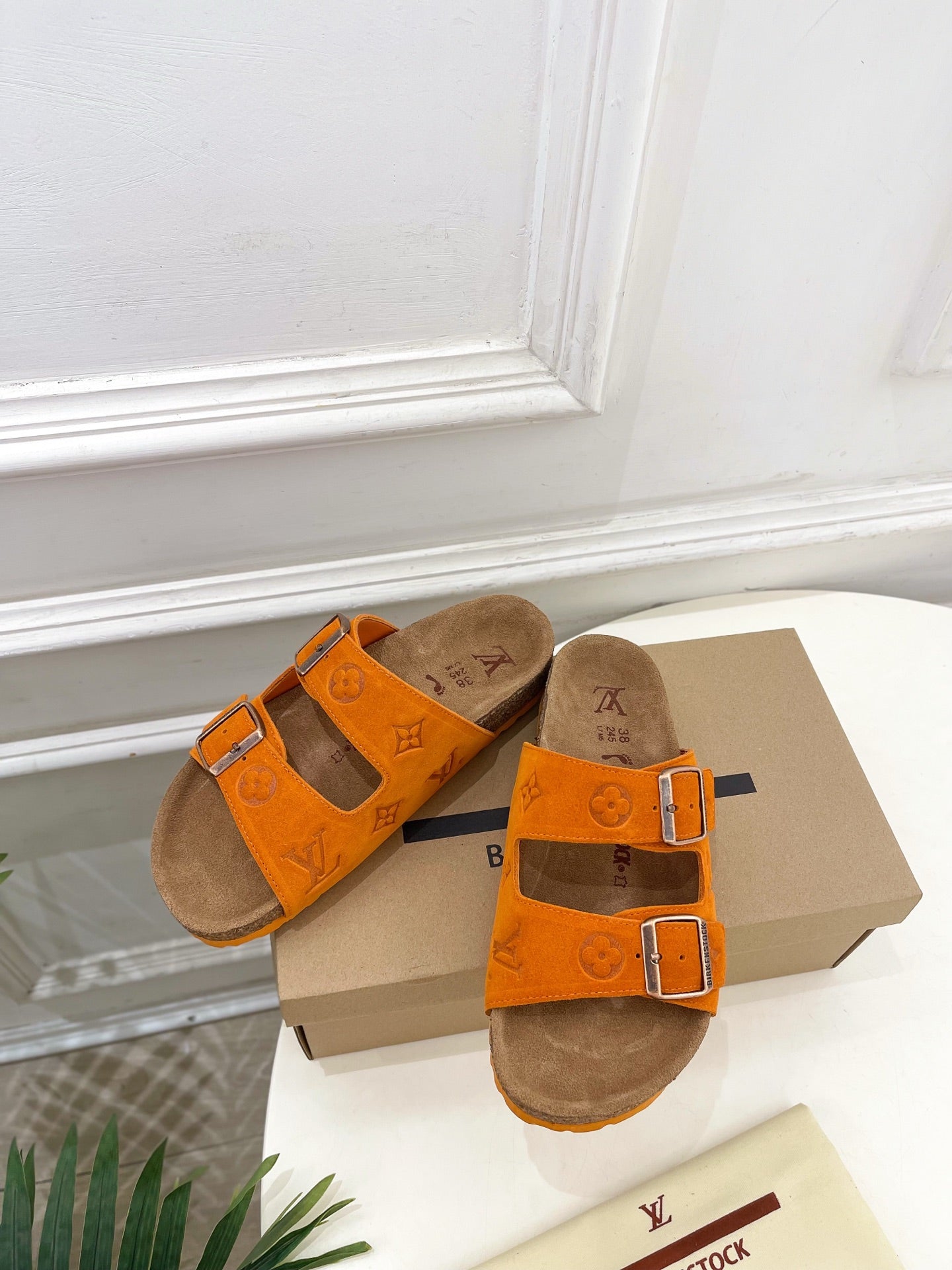 Orange Louis Vuitton sandals with two buckled straps and brown footbed, angled pair view.