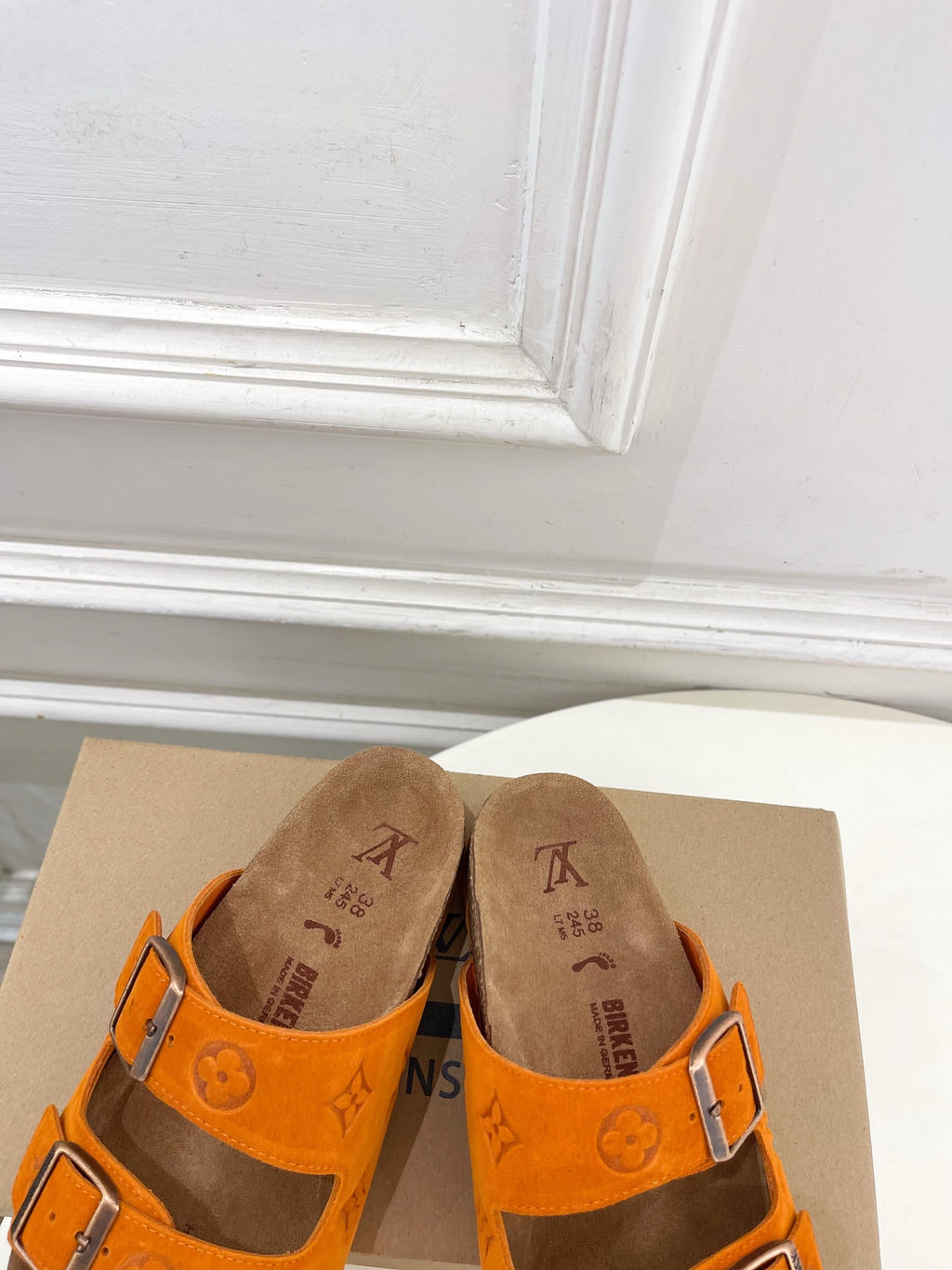 Orange Louis Vuitton sandals showing front buckles and monogram pattern, brown footbed.