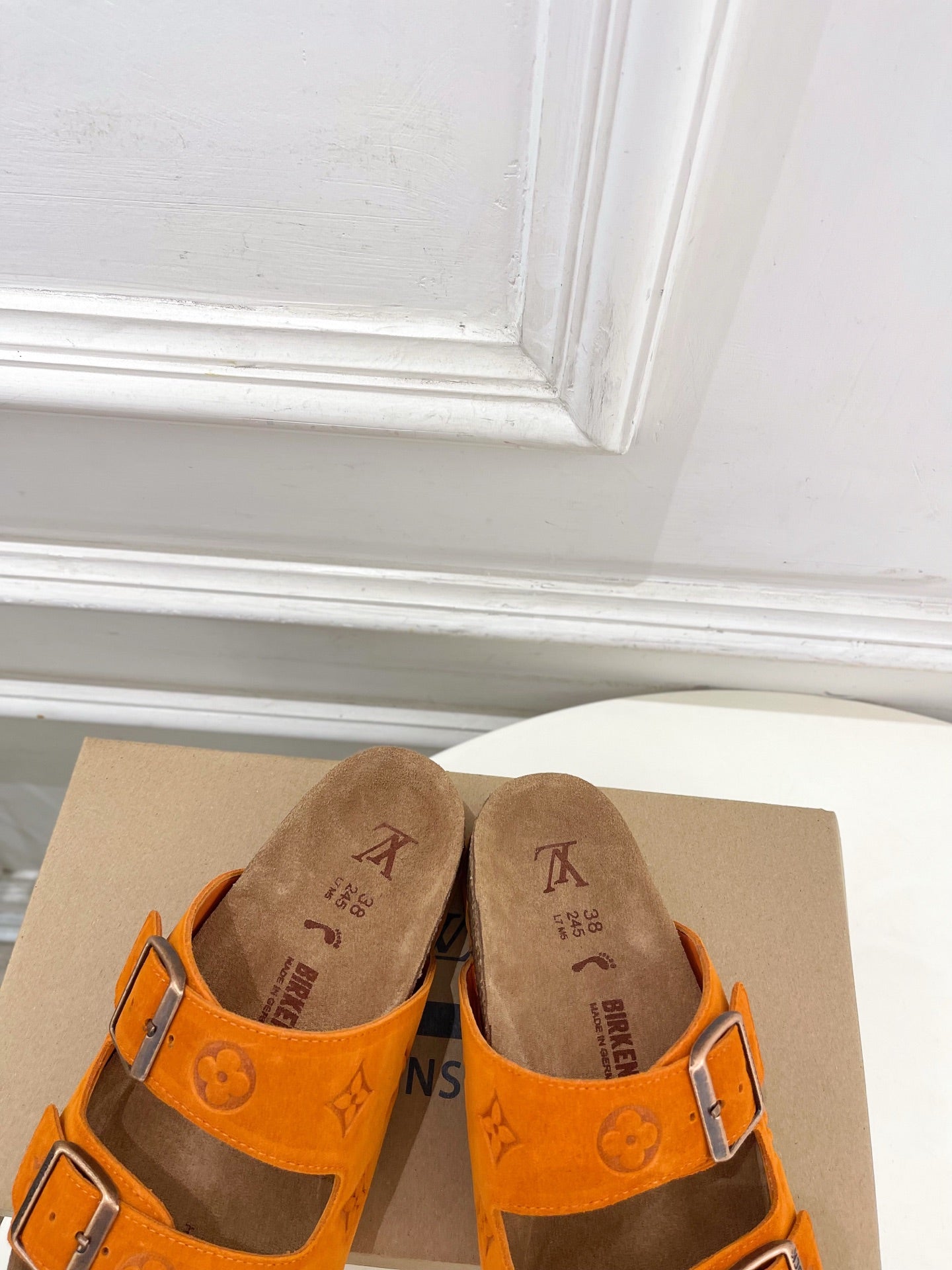 Orange Louis Vuitton sandals showing front buckles and monogram pattern, brown footbed.